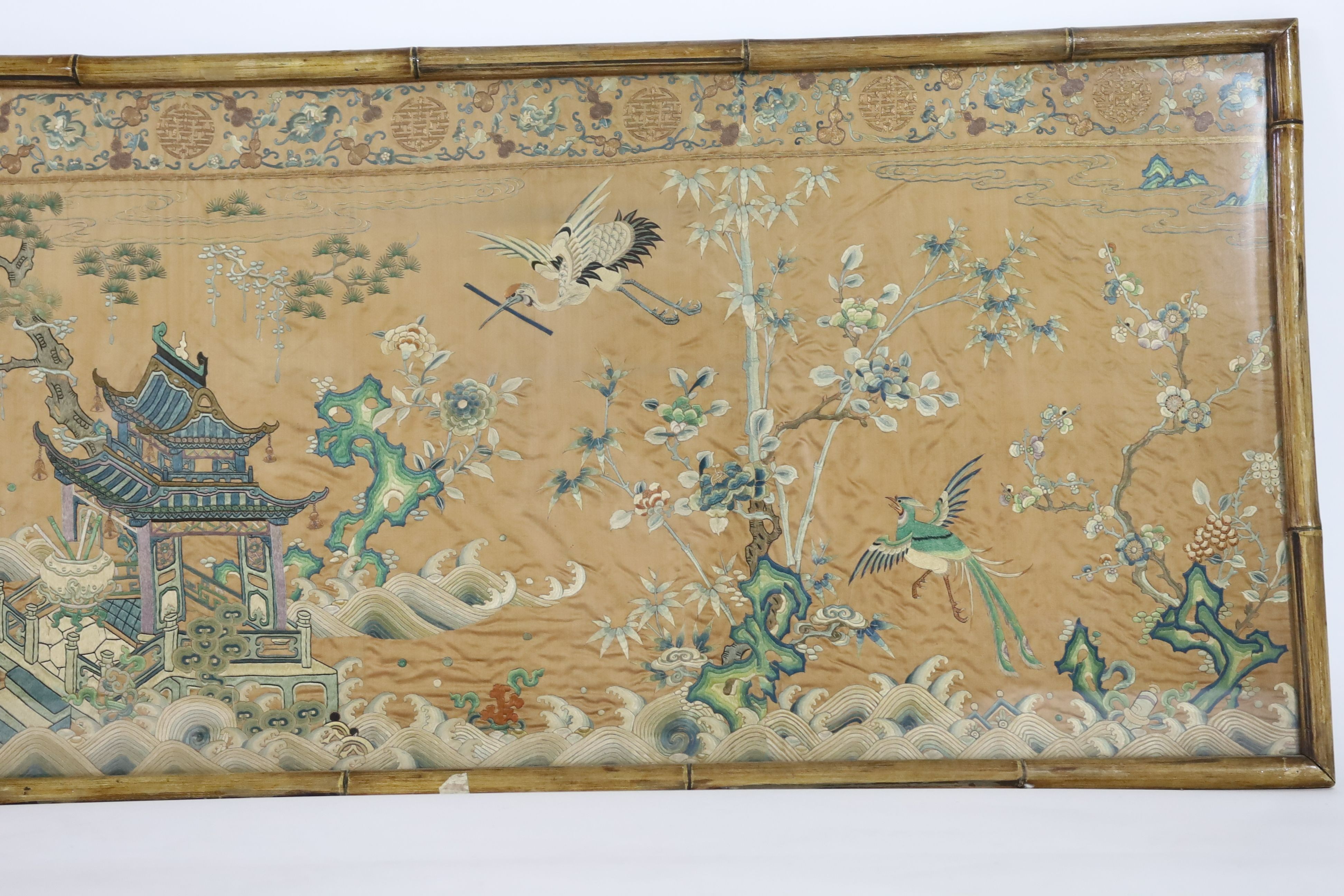 A Chinese apricot ground embroidered silk table frontal, late Qing dynasty, 58cm x 178cm, now trimmed and framed